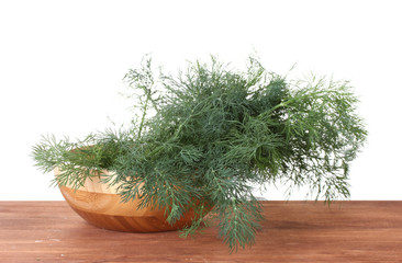 Dill in a wooden bowl on wooden