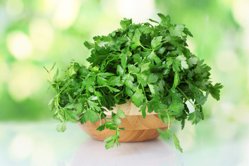Parsley in a wooden bowl on green background