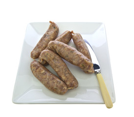 Pork sausages with caramelised red onions on white plate with kn