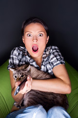 Fototapeta premium Woman sitting in her beanbag and embracing her cat