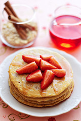 A stack of pancakes with fresh strawberries and syrup
