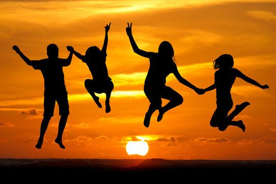silhouette of teens jumping in front of sunset