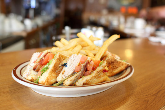 Delicious club sandwich with french fries at a diner.