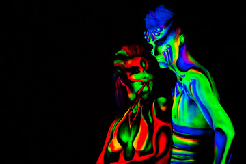 Man and woman with fluorescent bodyart. Black background. Studio