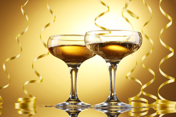 glasses of champagne and streamer on yellow background