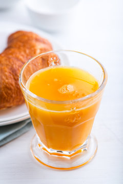 Glass of Orange Juice and Croissant on Table