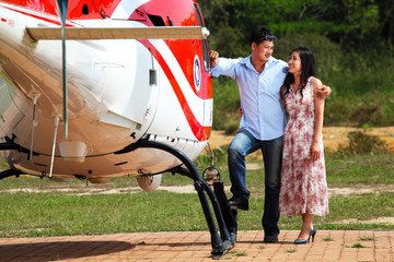 Happy loving couple traveling by helicopter and smiling