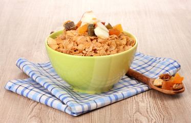 tasty cornflakes in bowl with dried fruits on wooden table