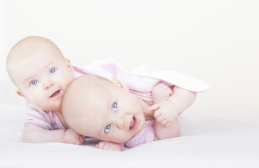 identical twin sister on bed learning how to crawl