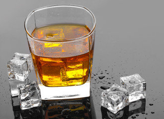 glass of scotch whiskey and ice on grey table