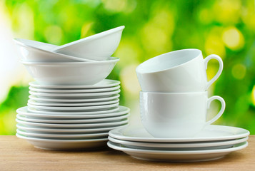 Clean dishes on wooden table on green background