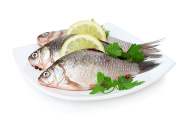 Fresh fishes with lemon and parsley on plate isolated on white