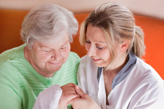 Altenpflegerin wäscht Seniorin die Hände