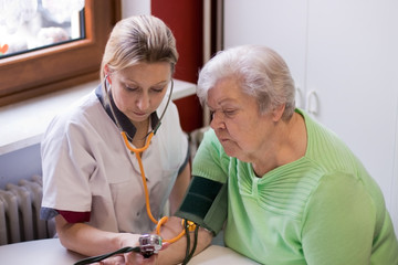 Altenpflegerin misst Blutdruck bei Patientin