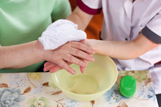Altenpflegerin wäscht Patientin die Hände