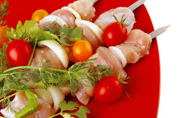 raw chicken kebabs on red