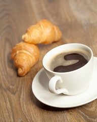 Breakfast with coffee and croissants in a basket on table