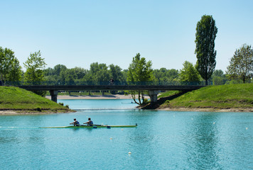 Two young men rowing on lake Jarun, bridge in back, Croatia