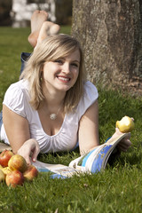 junge Frau liegt im Gras und liest