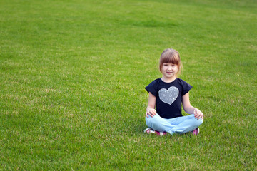 Cute smiling girl (7-years old) sitting on a lawn