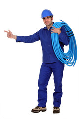 Electrician with cable pointing at copy space