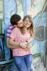Obraz na płótnie Canvas Young couple kissing near graffiti background.