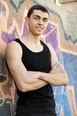 Teen boy near graffiti wall.