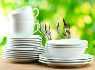 Clean dishes on wooden table on green background
