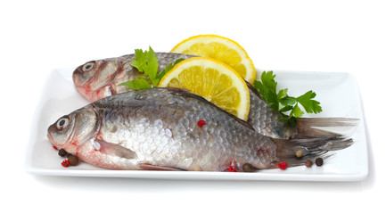 Fresh fishes with lemon and parsley on plate isolated on white