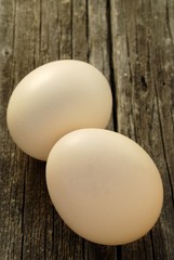 two chicken eggs on old wooden board