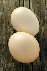 two chicken eggs on old wooden board