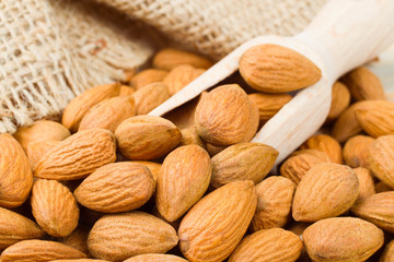 Almonds with wooden scoop on wooden table