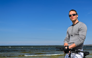 Portrait of handsome male with bicycle by the sea