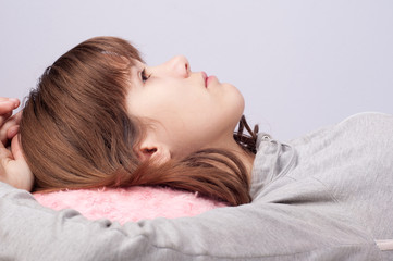 Cute serious teenage girl lies on the bed and looks up