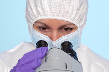 Female biochemist looking through microscope