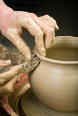 Fototapeta premium hands of a potter, creating an earthen jar on the circle