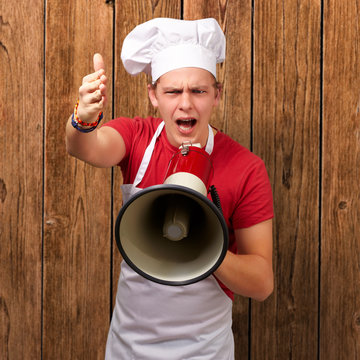 portrait of young cook man screaming with megaphone and gesturin