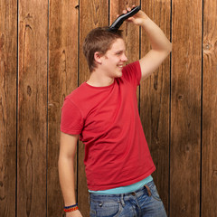 portrait of young man cutting his hair against a wooden wall