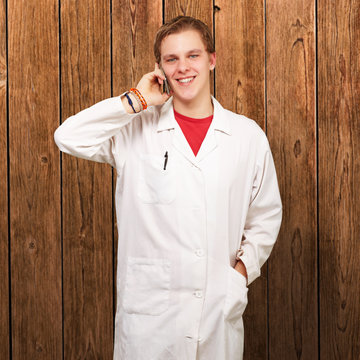 portrait of young academic talking on mobile against a wooden wa