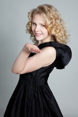 Young blonde girl blowing a kiss and posing in studio