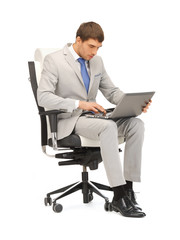 young businessman sitting in chair with laptop