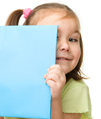 Cute little girl is hiding behind a book