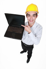 Young man in a hardhat with a laptop