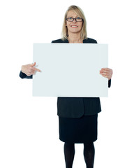 Fototapeta premium Corporate woman pointing towards blank billboard