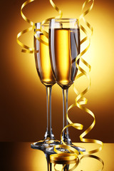 glasses of champagne and streamer on yellow background