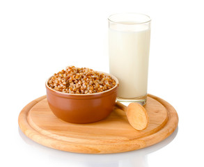 Boiled buckwheat in a brown bowl a glass of milk