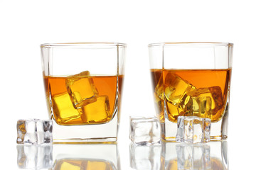 two glasses of scotch whiskey and ice isolated on white