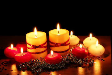 Beautiful candles and decor on wooden table on black background