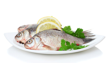 Fresh fishes with lemon and parsley on plate isolated on white