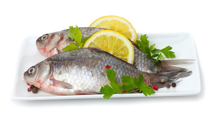 Fresh fishes with lemon and parsley on plate isolated on white